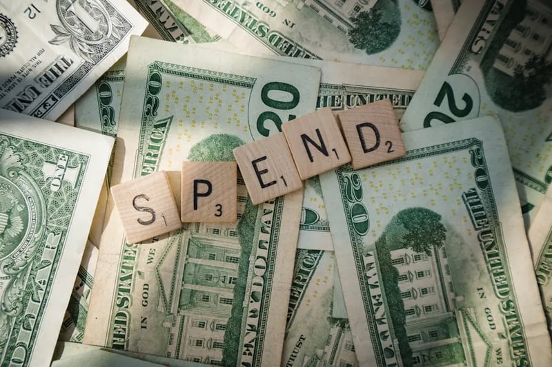 Scrabble tiles spelling the word "Investment" next to currency notes